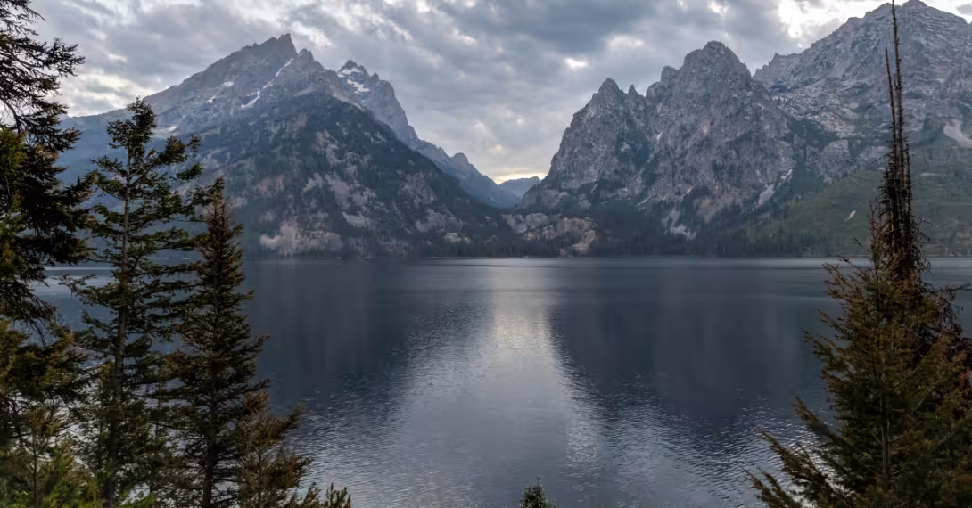 A body of water surrounded by trees and mountains